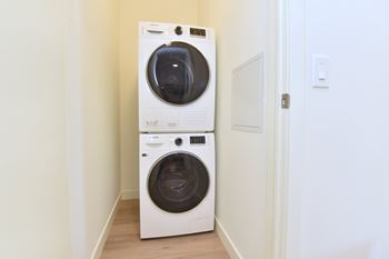 A white front loading washing machine in a narrow hallway